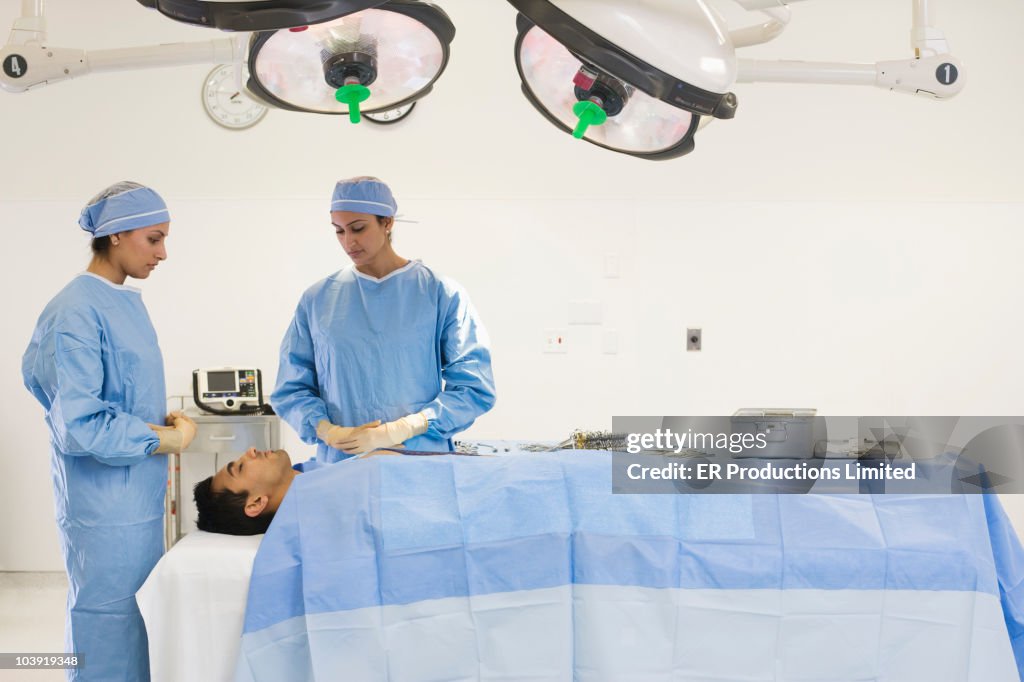 Asian surgeons preparing patient for operation