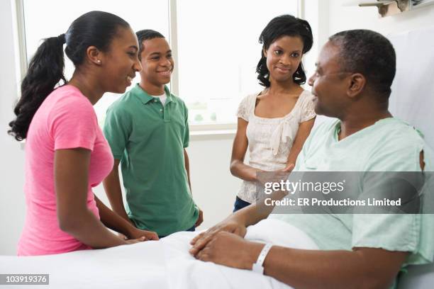 black man in hospital bed talking with family - er visit stock pictures, royalty-free photos & images