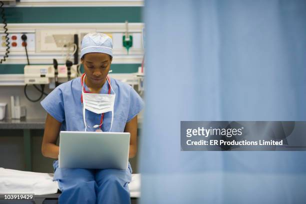 Black surgeon typing on laptop in hospital
