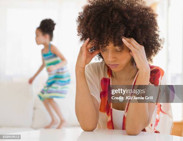 mother with headache and daughter jumping on sofa - headache child fotografías e imágenes de stock