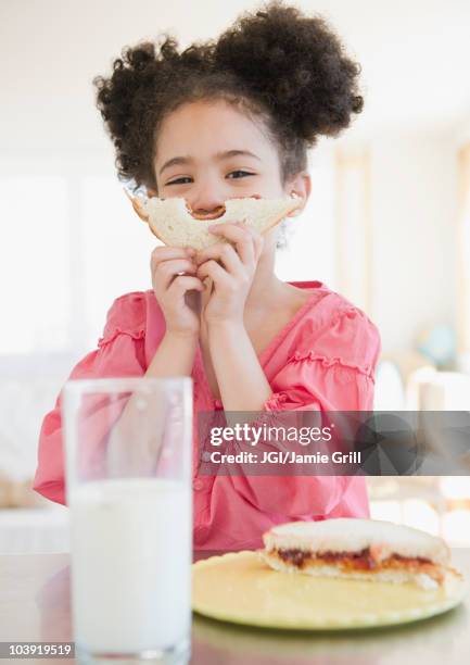 mixed race girl holding sandwich in front of face - peanut butter and jelly stockfoto's en -beelden