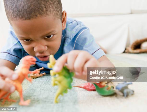 african american boy laying on floor playing with toy dinosaurs - toy animal bildbanksfoton och bilder