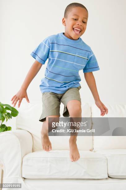 african american boy jumping off sofa - children only stock pictures, royalty-free photos & images