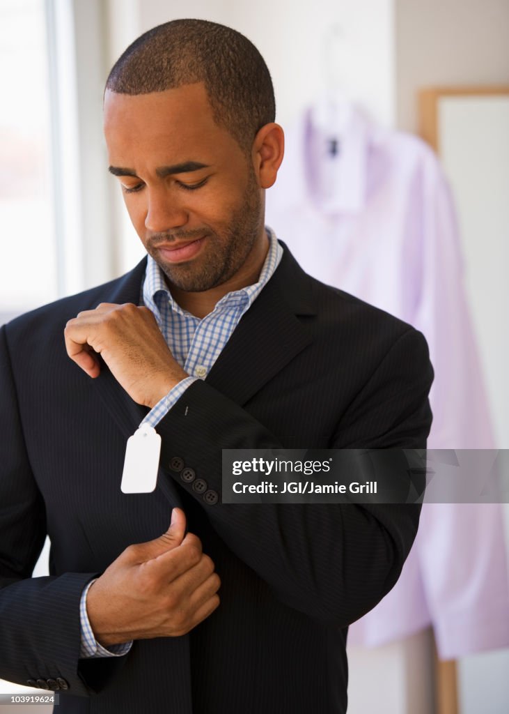 Mixed race shopper making face at price tag on jacket