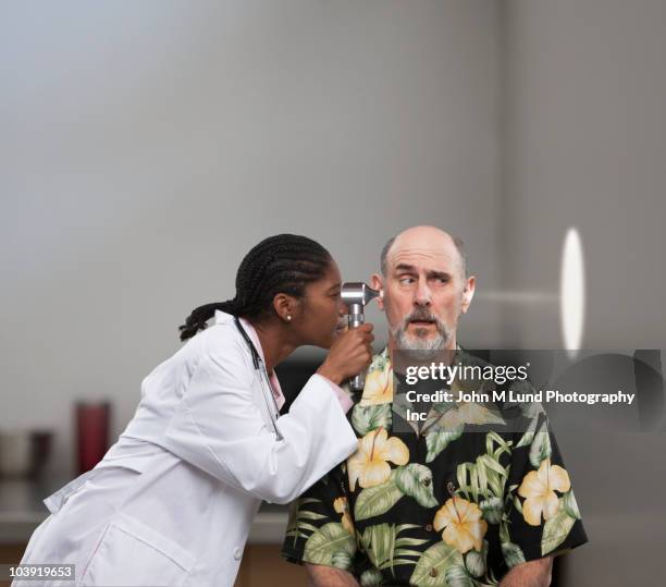 Doctor Shining Light Through Head Of Patient, ストックフォト