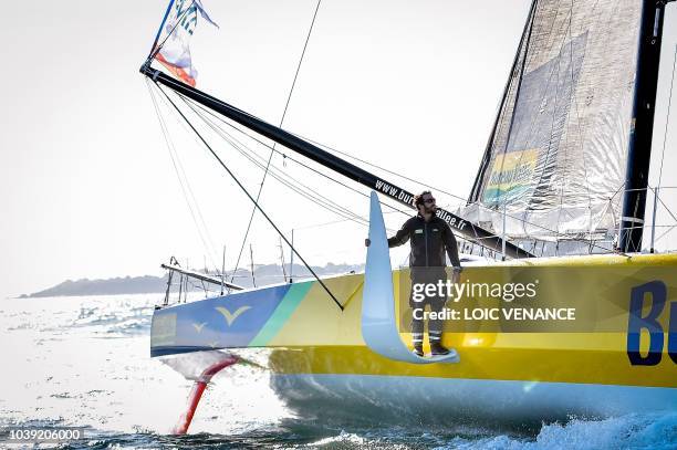 French sailor Louis Burton poses standing on a foil of his Imoca 60 monohull Bureau Vallee, as he sails from Lorient to Saint-Malo, on September 24 a...