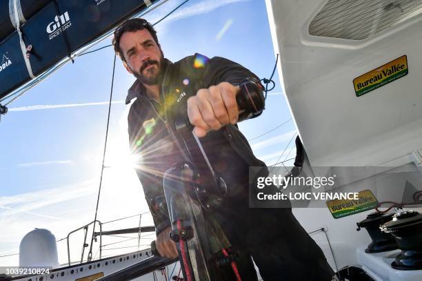 French sailor Louis Burton poses standing on a foil of his Imoca 60 monohull Bureau Vallee, as he sails from Lorient to Saint-Malo, on September 24 a...