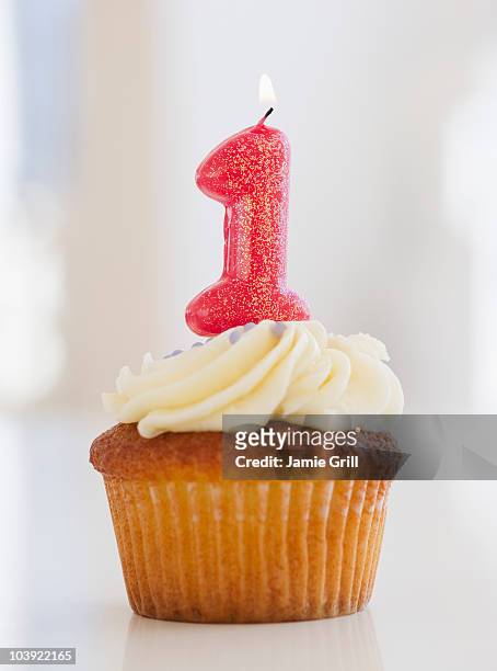 lit candle on cupcake for first birthday celebration - eerste verjaardag stockfoto's en -beelden