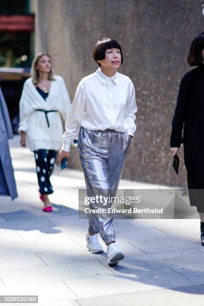 Angelica Cheung wears a white shirt, silver pants, white sneakers, during London Fashion Week September 2018 on September 17, 2018 in London, England.