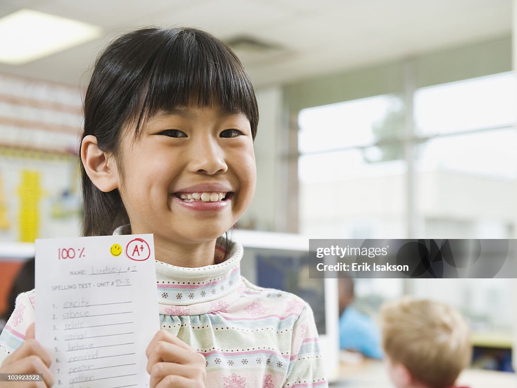 Elementary student holding an A grade paper