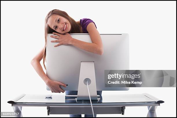 happy woman hugging a computer monitor - workoholic stock-fotos und bilder