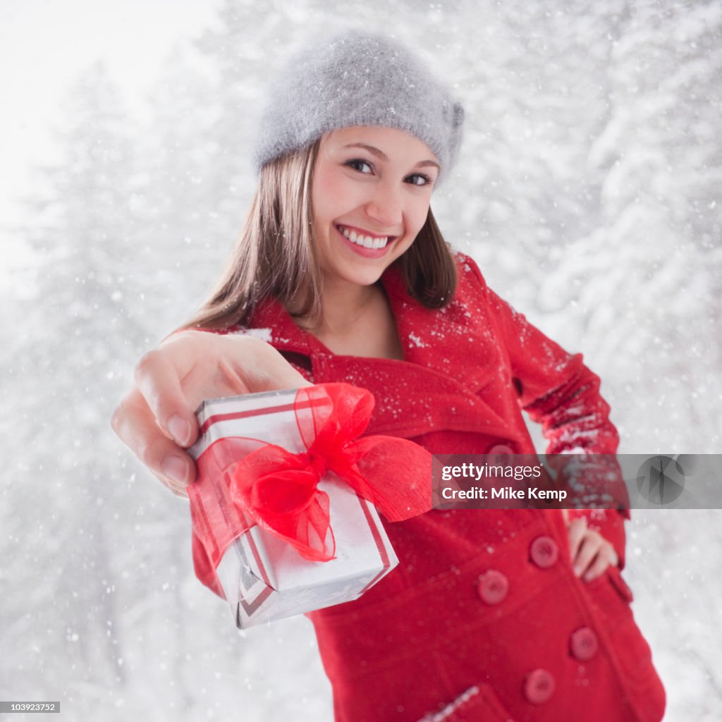 Smiling woman holding out a Christmas gift