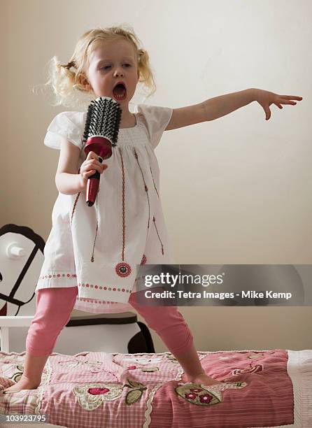 young girl singing on her bed - sauter sur le lit photos et images de collection