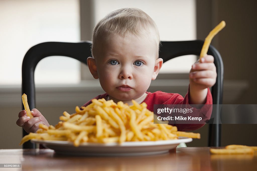 Toddler eating a large plate of French fries