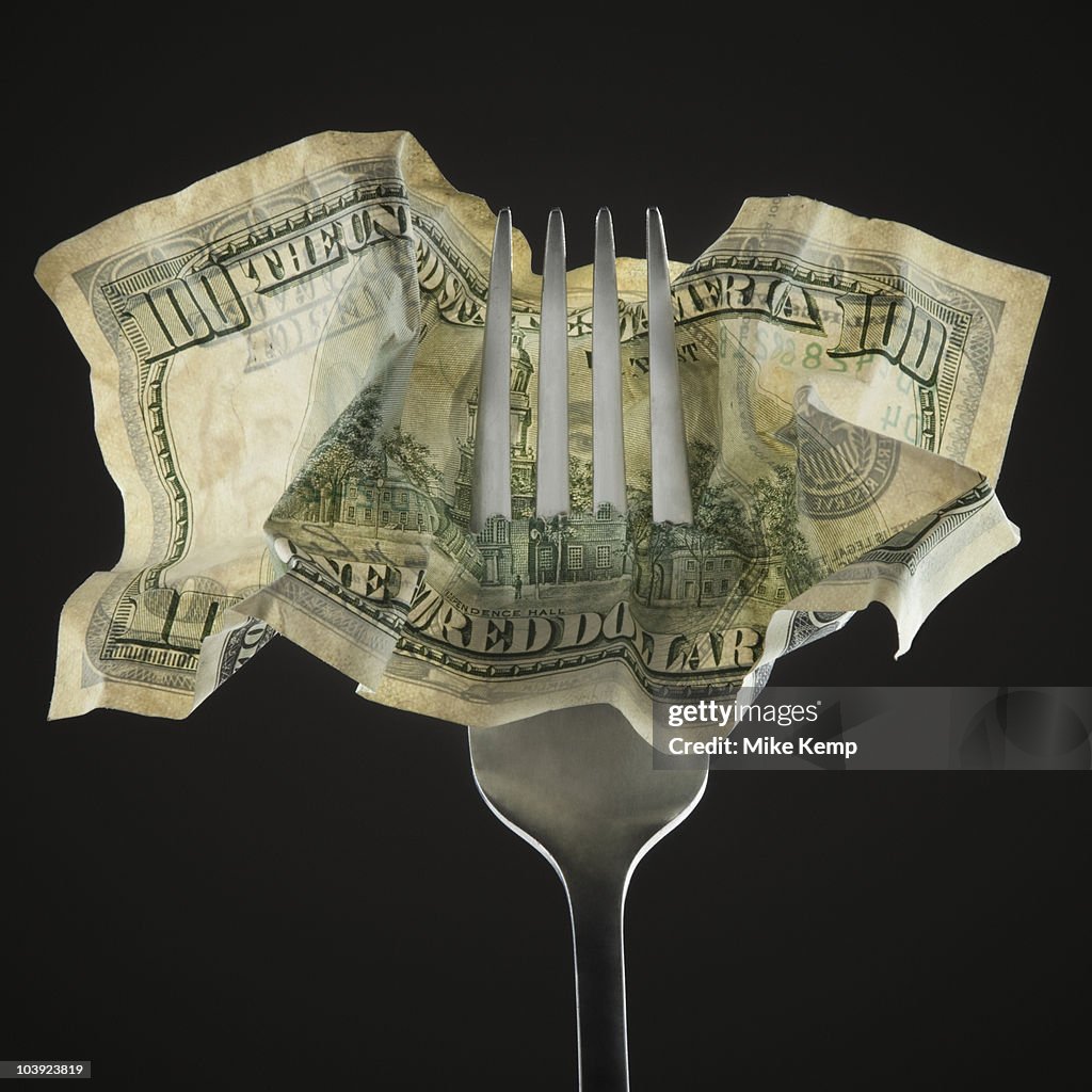 Fork pierced through American 100 dollar bill