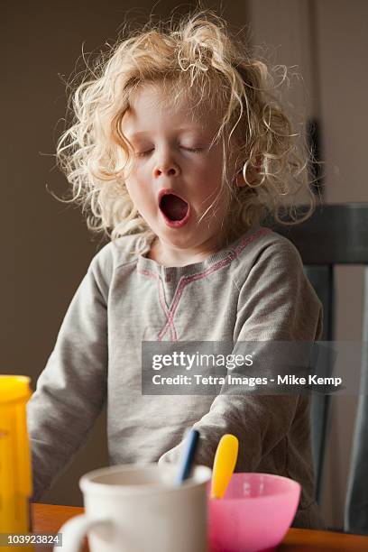 yawning child at the breakfast table - yawning stockfoto's en -beelden