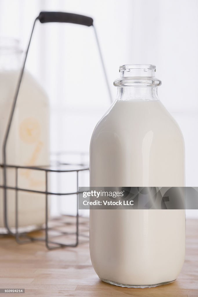 Open glass bottle of milk beside bottle carrier