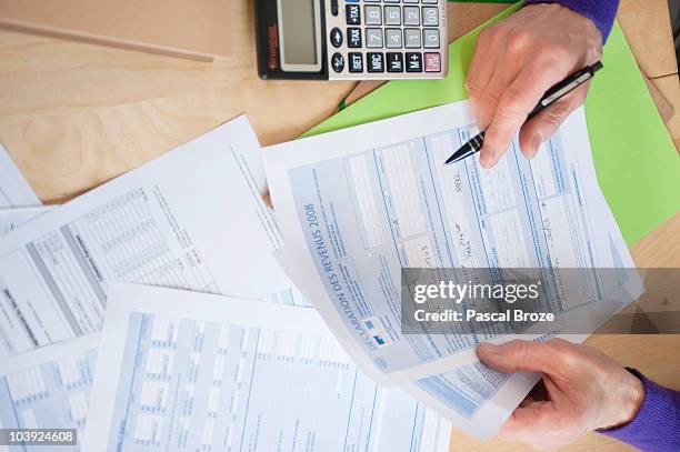 man's hands filling his tax form - tax form stock pictures, royalty-free photos & images