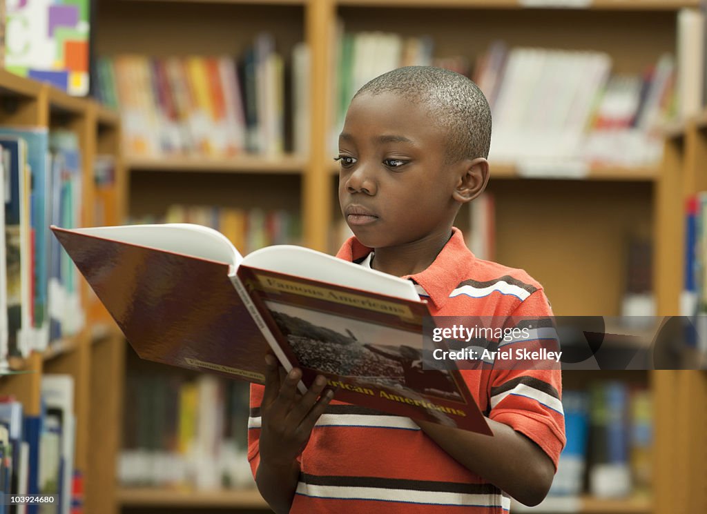 Black boy reading book in library