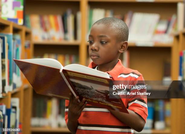 black boy reading book in library - boy library stock pictures, royalty-free photos & images