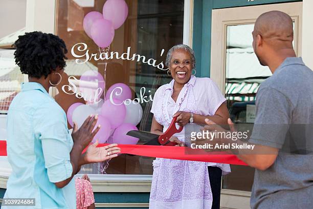 black shopkeeper cutting ribbon at storefront - opening event stock pictures, royalty-free photos & images