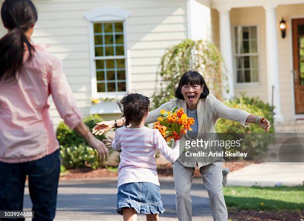 family welcoming woman with flowers - visit stock pictures, royalty-free photos & images