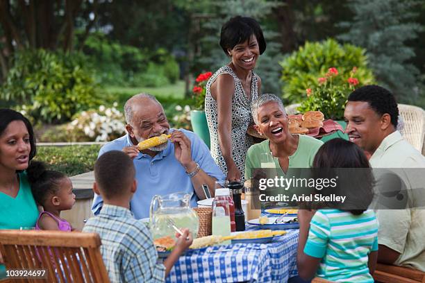 multi-generation black family eating at barbecue in back yard - familientreffen stock-fotos und bilder