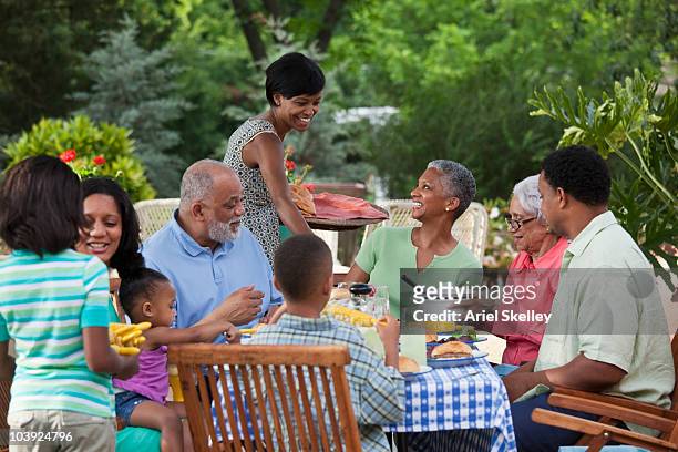 multi-generation black family eating at barbecue in back yard - riunione di famiglia foto e immagini stock