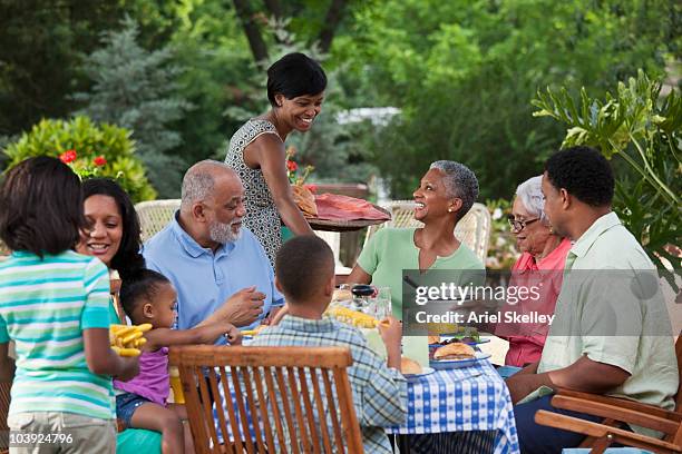 multi-generation black family eating at barbecue in back yard - 家族の集まり ストックフォトと画像