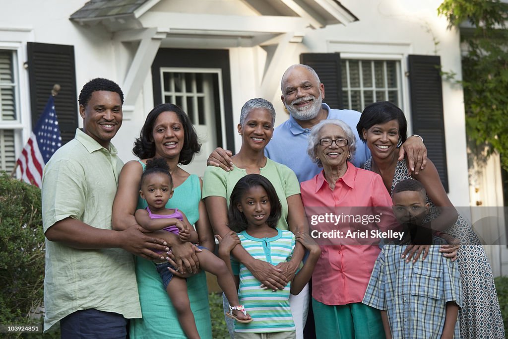 Multi-generation Black family posing in front of house