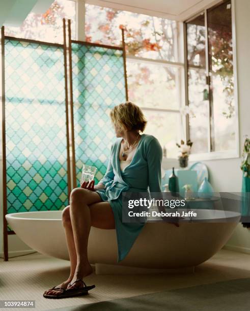 woman sitting on edge of bathtub - waters edge photos et images de collection