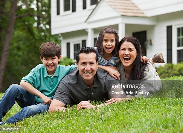 hispanic family laying on grass in front yard - family 2010 stock-fotos und bilder