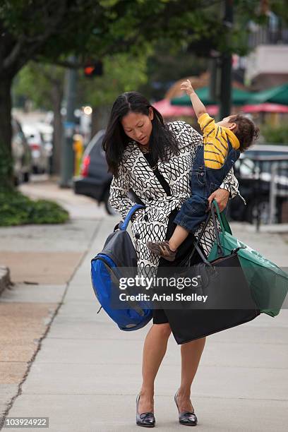 asian woman carrying baby and bags - multitasking mom stock pictures, royalty-free photos & images