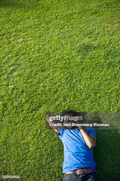 african american man using cell phone laying on grass - samuser stock pictures, royalty-free photos & images