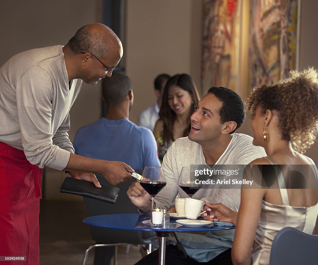Customers paying waiter at restaurant
