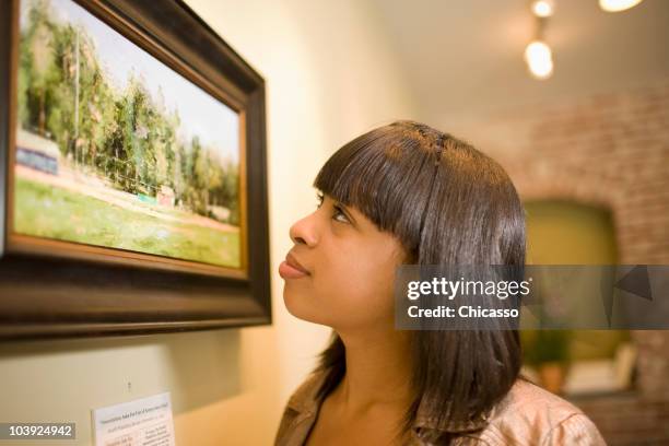 mixed race woman admiring painting in gallery - la art show stock pictures, royalty-free photos & images