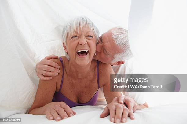caucasian couple playing under sheet in bed - white bed stockfoto's en -beelden