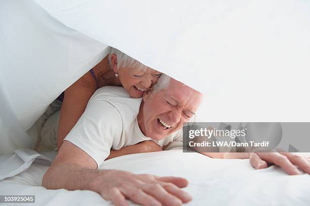 caucasian couple playing under sheet in bed - lwa dann tardif bed stock pictures, royalty-free photos & images