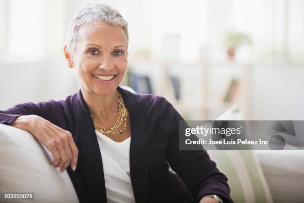 african american woman sitting on sofa - short stockfoto's en -beelden