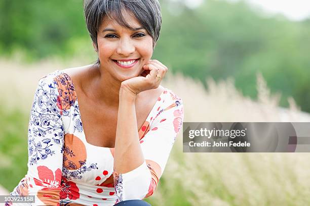 smiling mixed race woman in field - mature brunette woman stockfoto's en -beelden