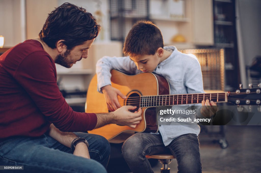 Young boy teaching to play guitar