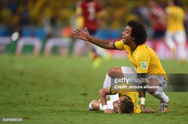 Neymar of Brazil lies on the pitch after picking up an injury next to Marcelo of Brazil during the FIFA World Cup 2014 quarter final match soccer...