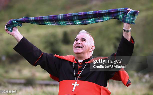 Cardinal Keith Patrick O'Brien unveils the world's first ever Papal visit tartan outside the Scottish Parliament, before handing it over to...