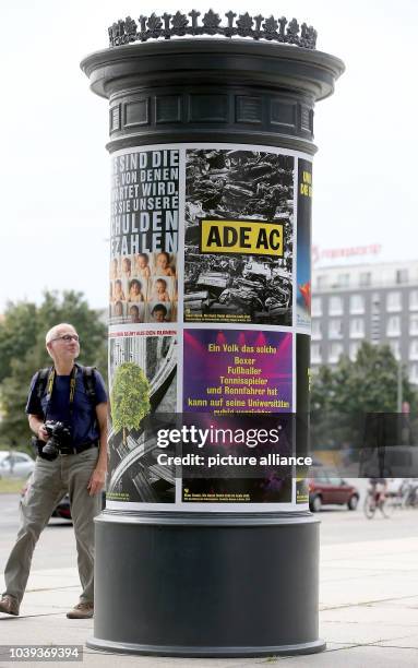 People walk past an advertising column with Klaus Staeck's poster outside of the New National Gallery in Berlin, Germany, 07 August 2014. His project...
