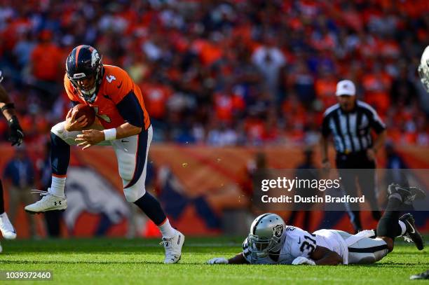 Quarterback Case Keenum of the Denver Broncos scrambles as defensive back Marcus Gilchrist of the Oakland Raiders defends in the fourth quarter of a...