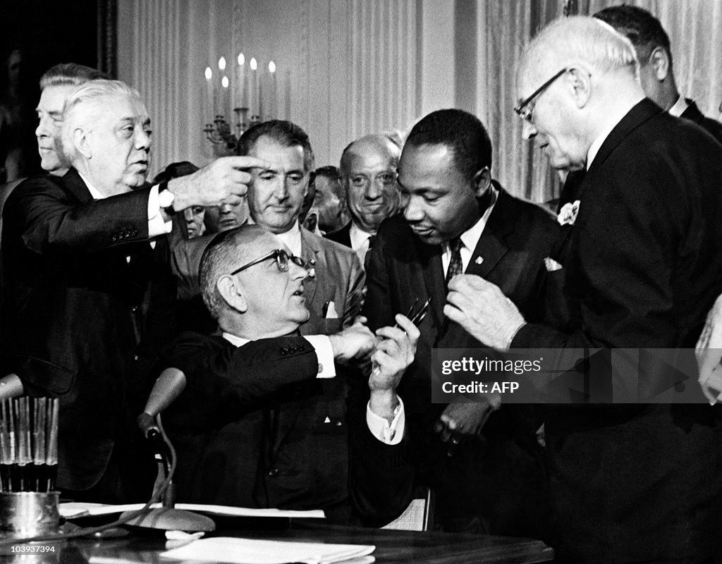 US President Lyndon B. Johnson hands a p