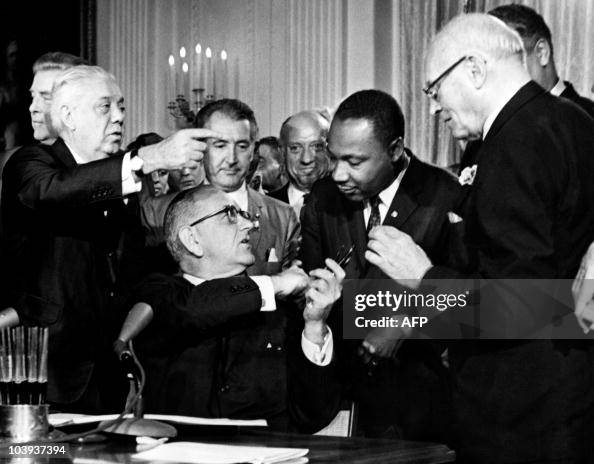 US President Lyndon B. Johnson hands a p