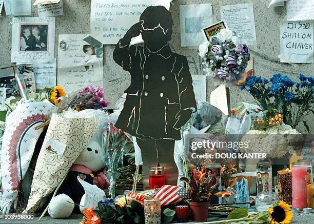 Metal sculpture of a young John F. Kennedy, Jr. Saluting his father's casket at his 1963 funeral stands among the floral tributes and other items...