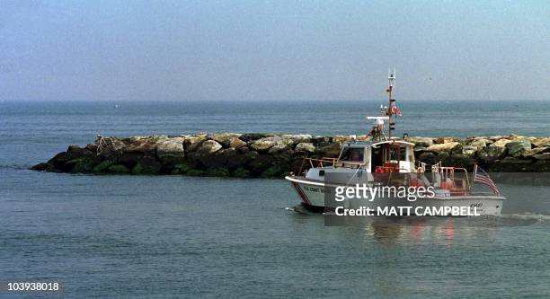 Coast Guard boat heads out from Mattituck Inlet on the North Shore of Long Island into Long Island Sound 17 July, 1999 to join the search for the...