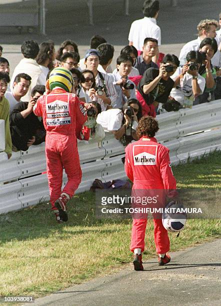 Ayrton Senna of Brazil and Alain Prost of France walk towards their pit 21 October 1990 after they crashed in the first turn right after the start.